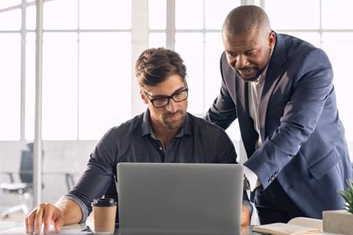 Two office workers looking at a laptop computer